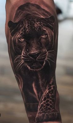 a man's arm with a black and grey tattoo of a cheetah