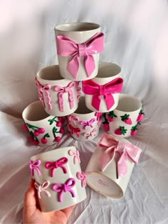 a hand is holding several cups with bows on them