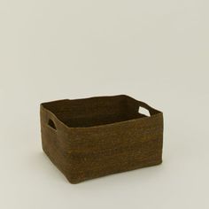 a brown basket sitting on top of a white table next to a black object in the middle