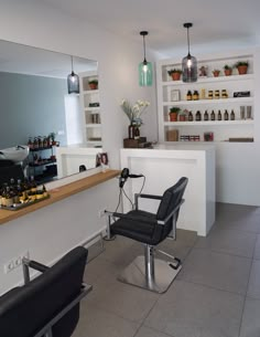 a hair salon with chairs and shelves full of bottles on the wall behind it,