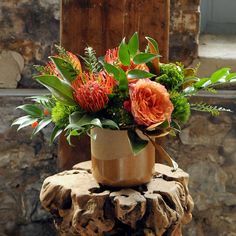 an arrangement of flowers is sitting on a rock