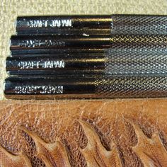 four brushes are lined up on top of a leather case, which has been stitched together