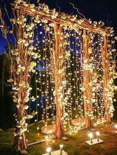 an outdoor ceremony with candles and flowers on the grass, surrounded by trees that have been decorated with lights