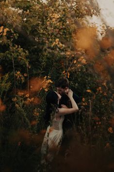 a bride and groom embracing in the tall grass