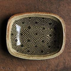 a brown and black bowl sitting on top of a wooden table