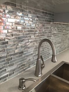 a stainless steel kitchen sink and faucet in front of a tiled backsplash