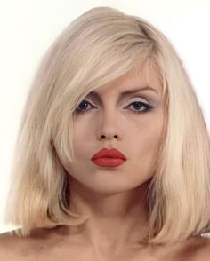 a woman with blonde hair and bright red lipstick on her lips is posing for the camera