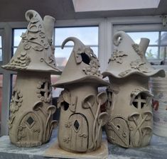 three clay houses sitting on top of a table next to each other with windows in the background