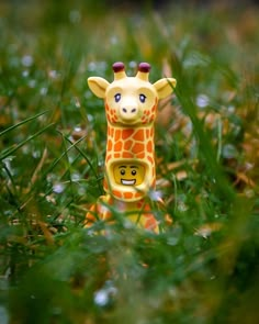 a toy giraffe is standing in the grass