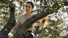 a woman standing on top of a tree branch