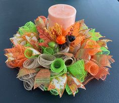 a candle that is on top of a table with some ribbons around it and leaves