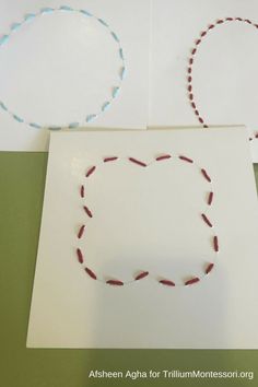 two pieces of white paper with red and blue thread on them