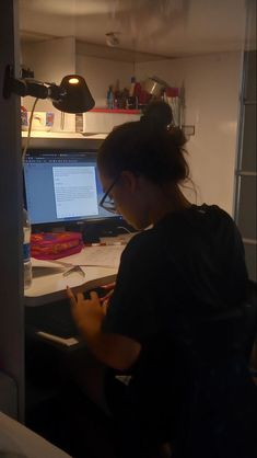 a woman sitting in front of a computer desk with a laptop on top of it