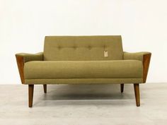 a green couch sitting on top of a white floor next to a wooden frame chair