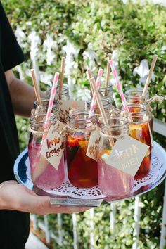 there are many drinks in mason jars with straws on the tray and paper signs attached to them