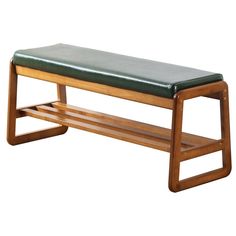 a wooden bench with a green leather seat on it's backrest and shelf for storage