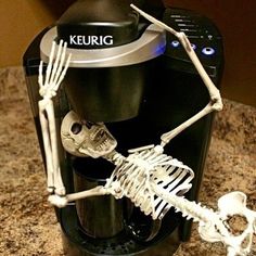 a coffee maker with skeleton figurines on it