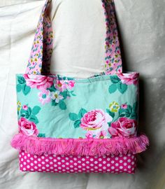 a pink and green flowered purse on a white sheet with polka dots, flowers and leaves