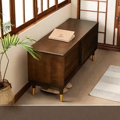 a wooden table with a plant on it in front of a window and an area rug