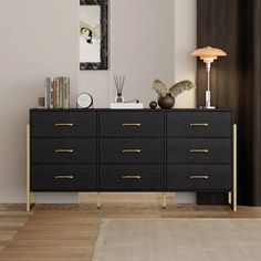 a black and gold dresser in a living room next to a painting on the wall