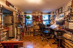 a room filled with lots of books and desks next to a wall covered in pictures