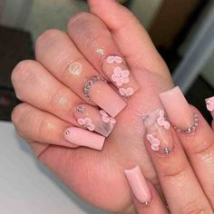 a hand with pink flowers on it and some glitters in the nail polishes