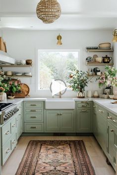 a kitchen filled with lots of green cabinets and white counter tops, along with a rug on the floor