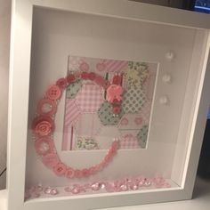 a white frame with pink buttons and flowers in the center, on top of a table