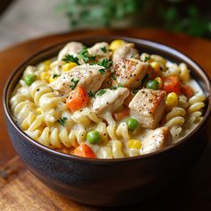 a bowl filled with pasta and chicken on top of a wooden table