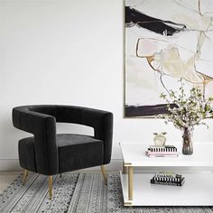 a living room with two black chairs and a white coffee table in front of a painting