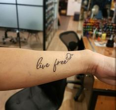 a person with a tattoo on their arm that says live free in cursive writing