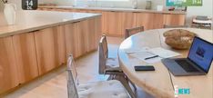 an open laptop computer sitting on top of a wooden table in a kitchen next to a window