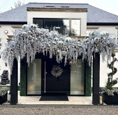 the front entrance to a house decorated with silver and white christmas decorations on it's pillars