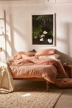 an unmade bed sitting in a bedroom next to a window with plants on the wall