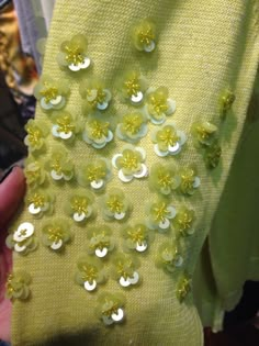 a person is holding a yellow piece of cloth with flowers on it and sequins in the middle