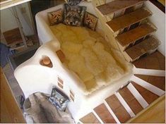 a dog bed made to look like a house with fur on the floor and stairs