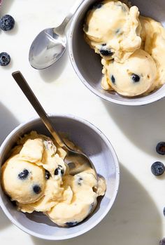 two bowls filled with ice cream and blueberries on top of a white countertop