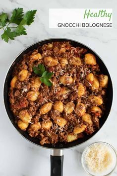 a pan filled with meat and vegetables on top of a white counter next to a bowl