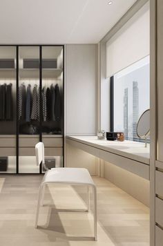 a walk in closet with clothes on hangers and a bench next to the window