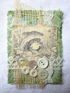 buttons and lace are attached to a piece of fabric with an image of a frog on it