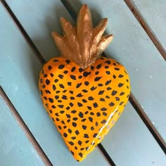 a yellow and black heart shaped decoration on top of a blue wooden table next to a gold pineapple