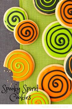 some cookies are decorated with swirl designs on green and orange paper towels next to each other