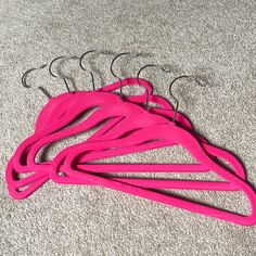 five pink hangers on carpet with one hanging off the floor and three in the middle