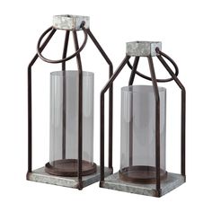 two metal and glass candle holders sitting on top of each other