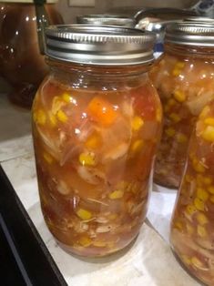 three jars filled with food sitting on top of a counter next to a stovetop