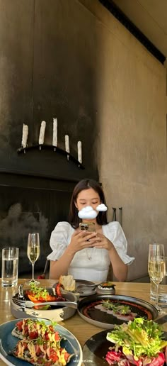 a woman sitting at a table with plates of food and wine in front of her