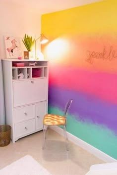 a chair sitting in front of a rainbow painted wall