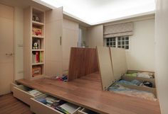 an empty room with wooden furniture and storage drawers on the floor, in front of a bookshelf