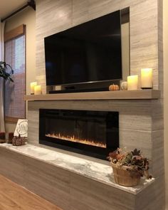 a living room with a fireplace and television mounted on the wall next to a window