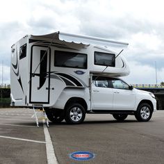 a white truck with a camper attached to it's bed parked in a parking lot